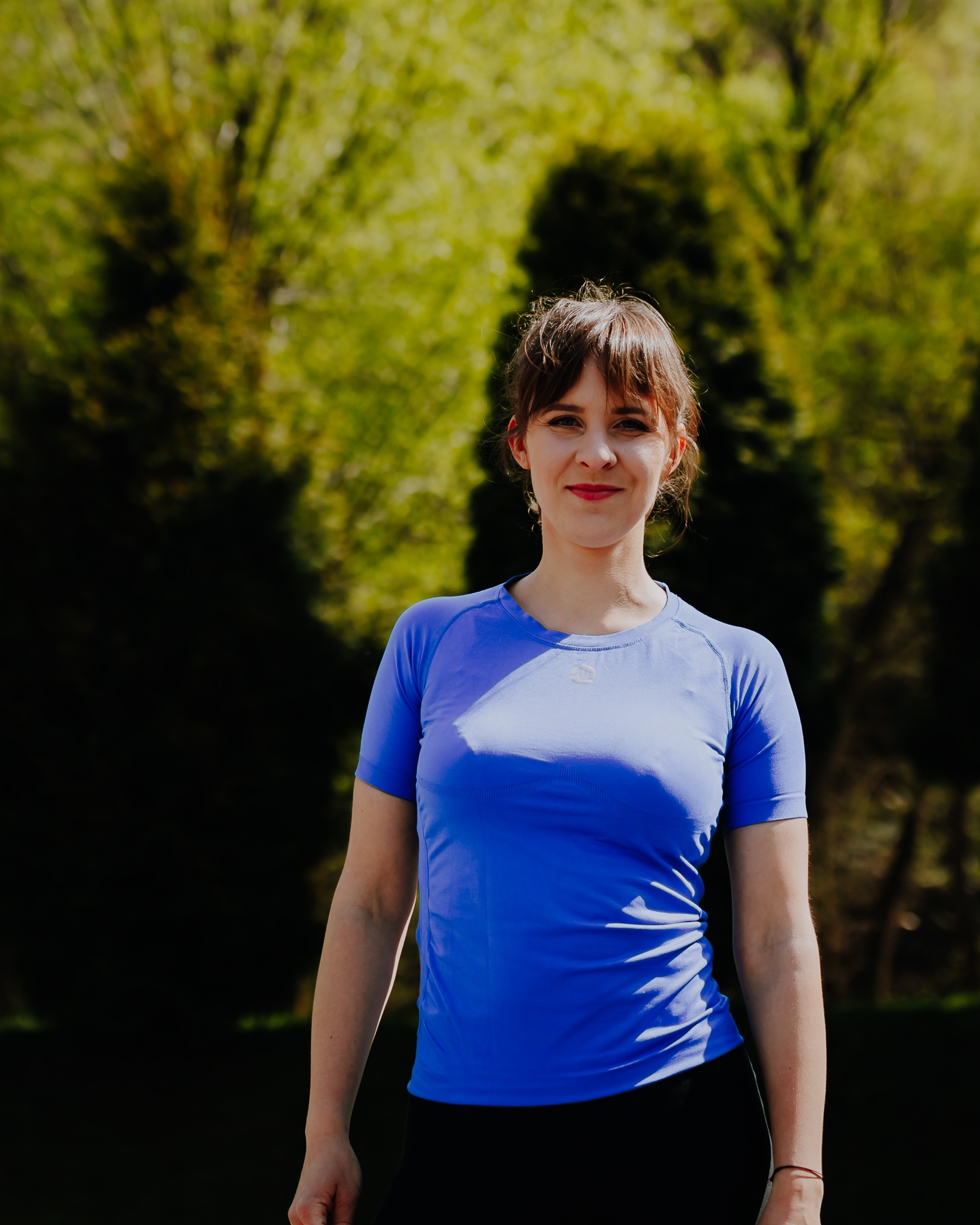 Weronika Nycz, trenerka personalna z Bielska-Białej — portret w naturalnym świetle na tle zieleni.
